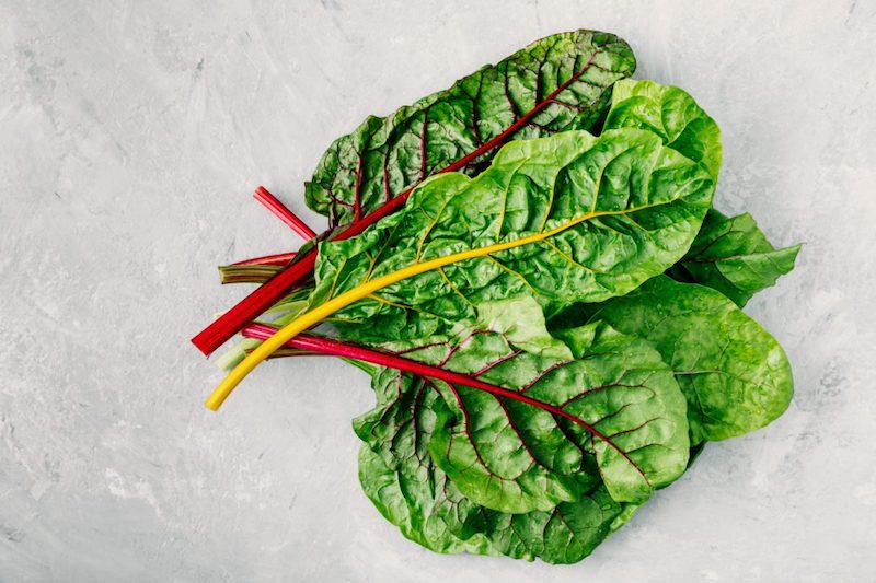Fresh raw swiss rainbow chard leaves on gray stone background. Top view