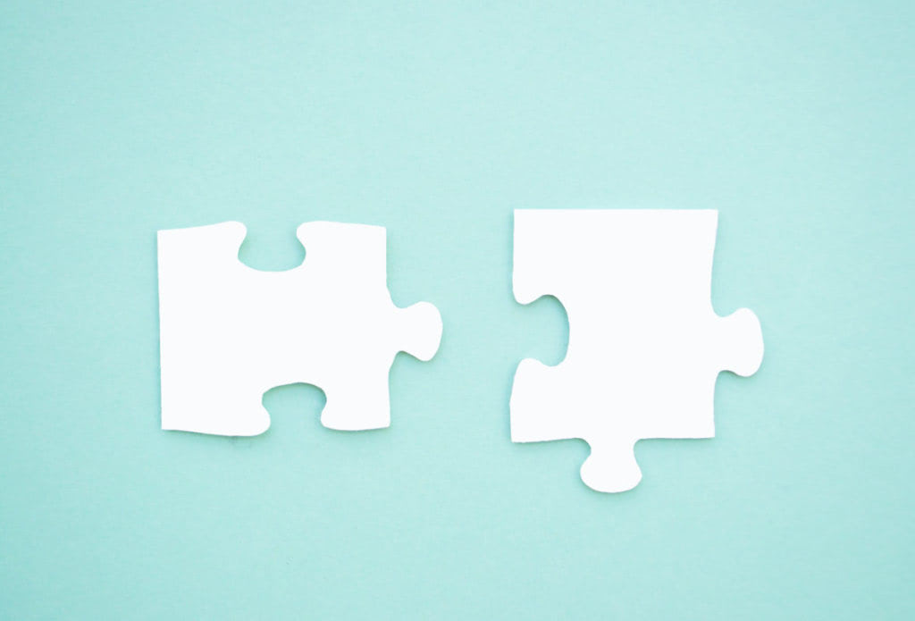 Two puzzle pieces on blue background as a symbol of autism awareness.