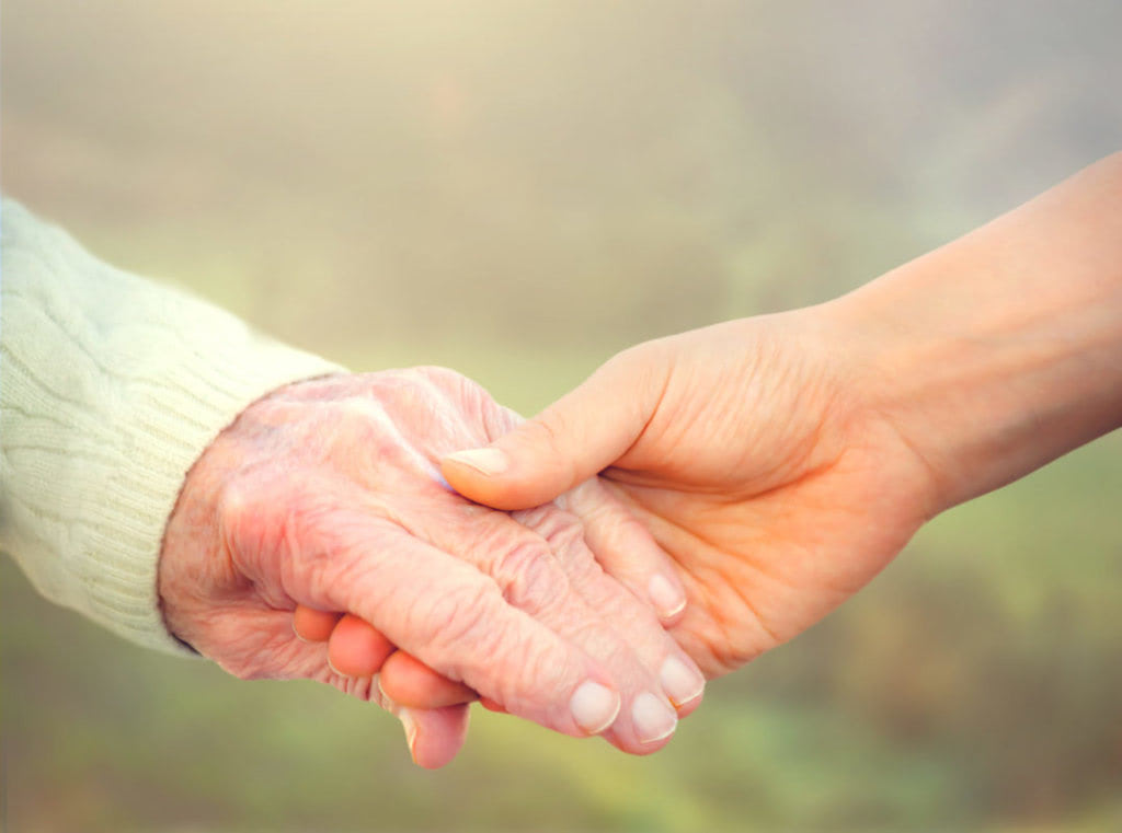 Elderly woman holding hands with young caretaker