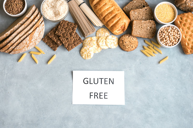 Gluten free food. Various gluten free pasta, bread, snacks and flour on light gray background, top view, copy space.