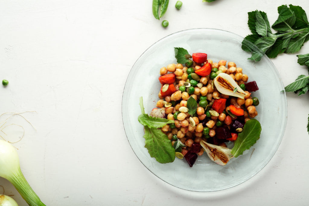Fresh chickpea salad with mint and vegetables on white rustic background. Healthy lunch concept.  Composition with copy space