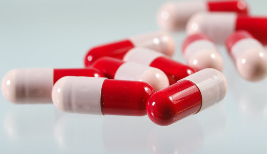 Heap of red and pink proibiotics capsule on white