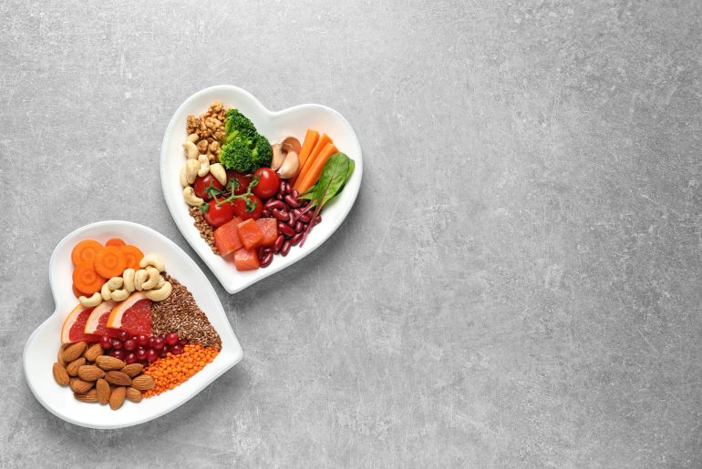 Plates with heart-healthy diet products on grey background, top view. Space for text